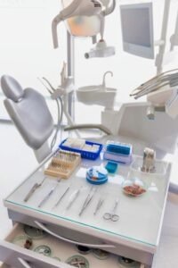 Instrumentet dentare të vendosura pranë një karrigeje dentare, duke treguar se ato mund të pastrohen në një pastrues ultrasonik.